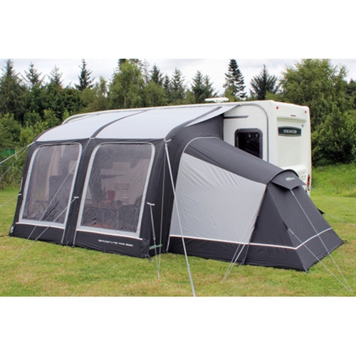 Fortelt-anneks til campingvogn på gressplen med trær, inkluderer vinduer og barduner.