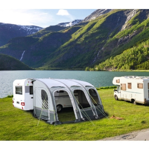 Fortelt med buer og vinduer ved campingvogn nær innsjø og fjell.