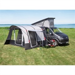 Telt forbundet til varebil på gress ved vann, med vinduer og inngang, klar for camping.